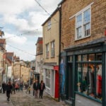 Narrow street lined with shops and pedestrians