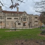 Stone Tudor-style building with a lawn and trees